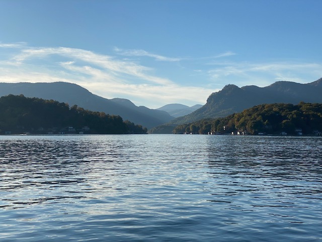 A serene lake nestled among tall mountains and lush green trees under a clear blue sky