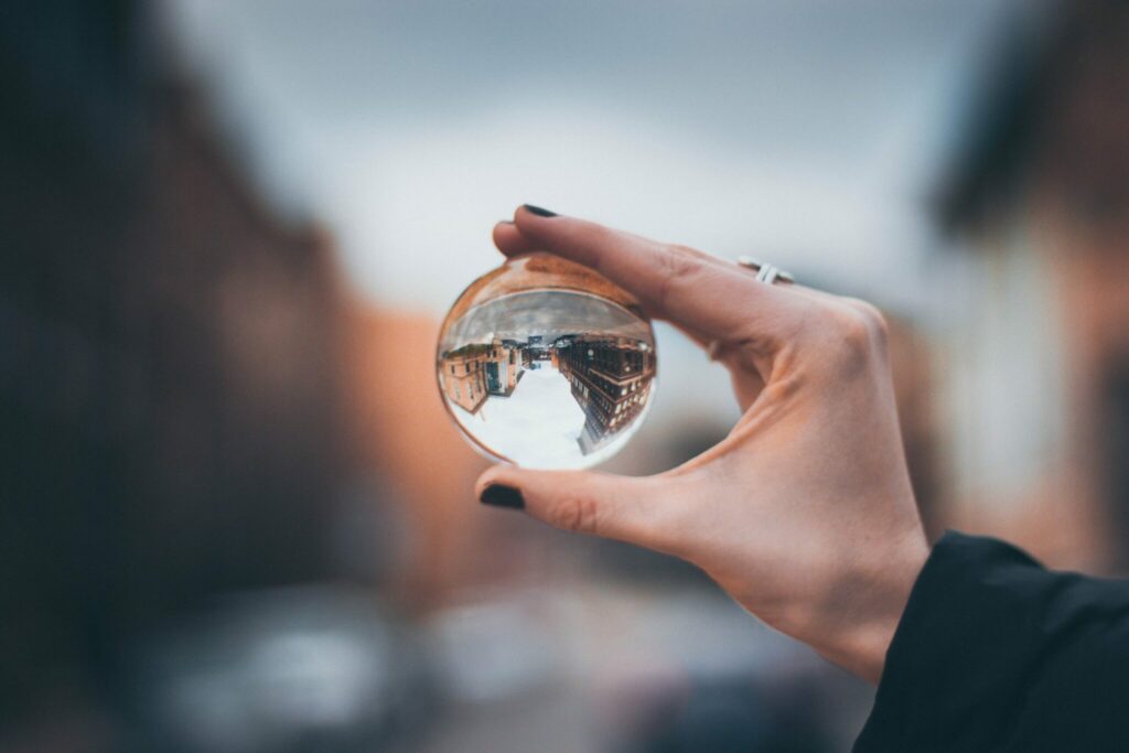A person holds a glass ball reflecting a city skyline