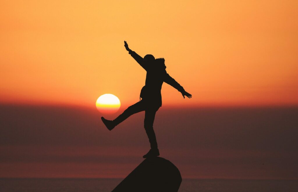 Silhouette of a person leaping on a rock