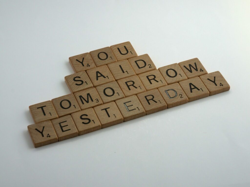A close-up of Scrabble tiles showing the phrase "you said tomorrow yesterday" on a game board