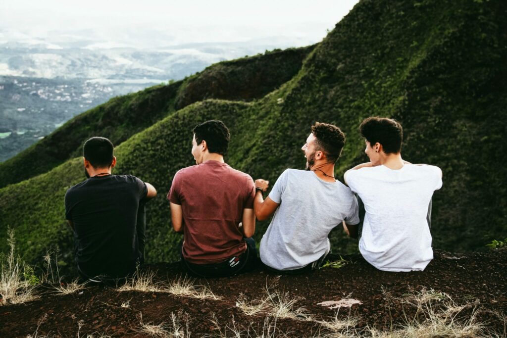 Three young men sit on a hill