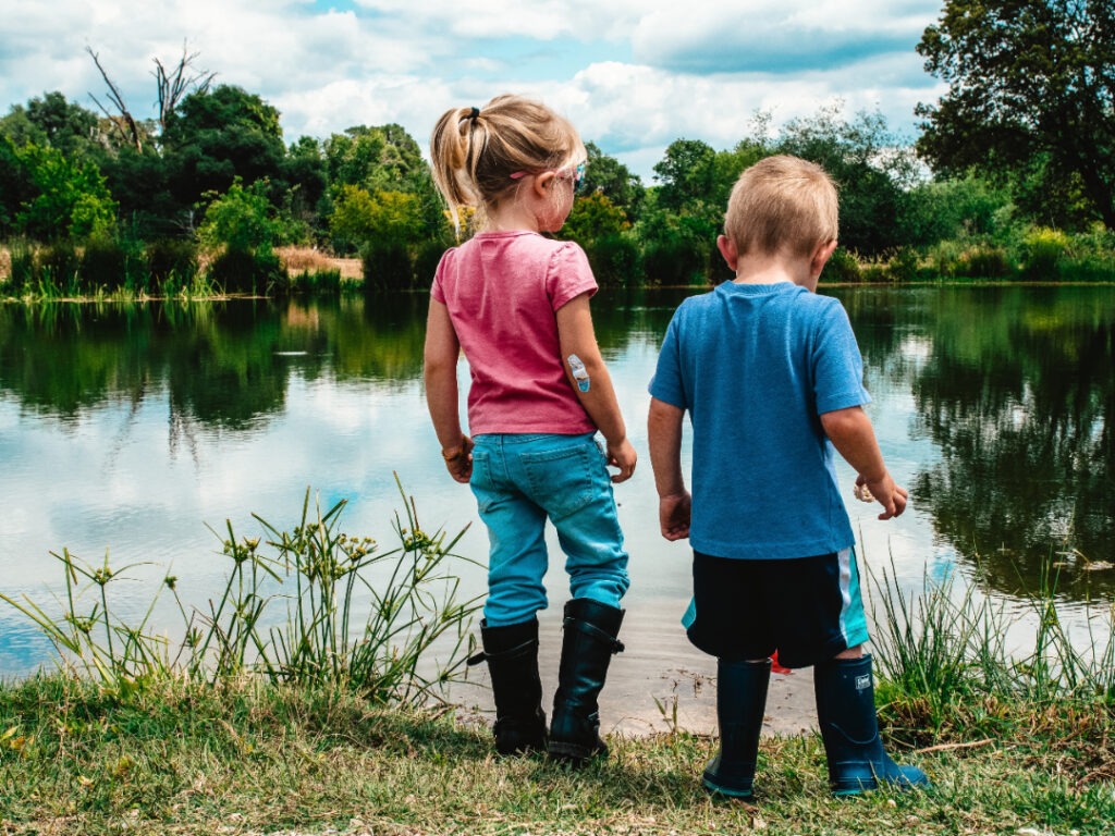 Two kids are near a calm lake