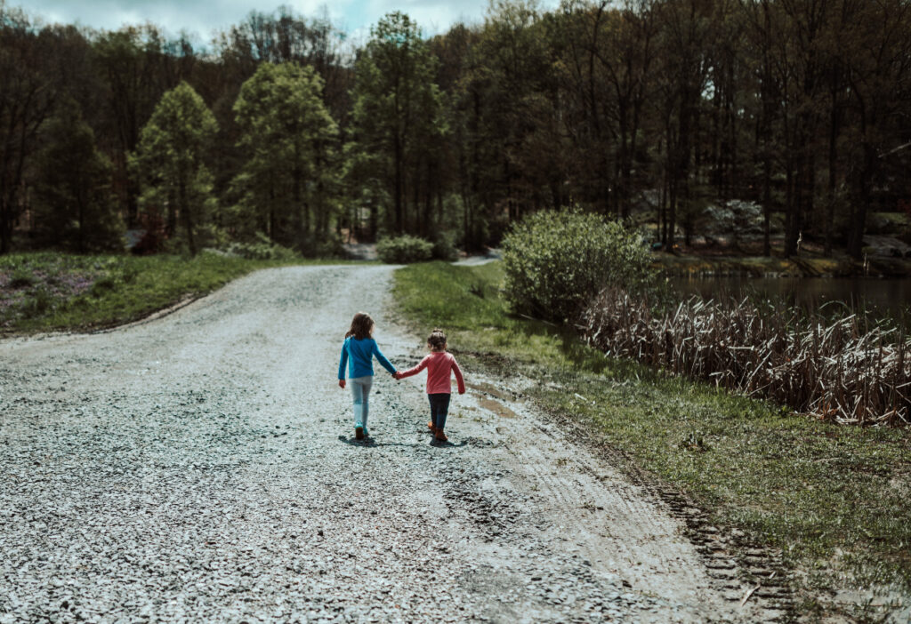 Two children stroll down a dirt road